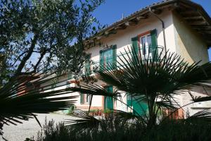 uma casa com janelas verdes e brancas e palmeiras em Il Grillo Parlante em Monforte dʼAlba