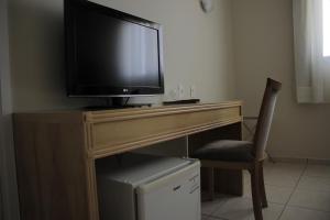 une télévision installée au-dessus d'un bureau en bois avec une chaise dans l'établissement Harbor Self Graciosa Hotel, à Quatro Barras