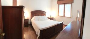 um quarto com uma cama com lençóis brancos e uma janela em Holiday House, São Roque do Pico em Cais do Pico