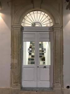 una porta bianca con finestra in un edificio di A'Storia a Siracusa