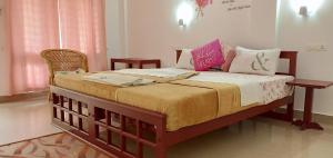 a bedroom with a large bed with pink and white pillows at Periyar Inn in Thekkady