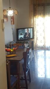 a living room with a table and a tv with a man on it at appartamento Lory in Campomarino