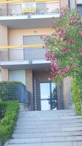 a building with stairs and a balcony with pink flowers at appartamento Lory in Campomarino