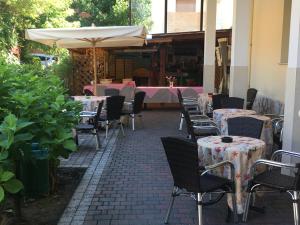 an outdoor patio with tables and chairs and an umbrella at Hotel Adriana in Bellaria-Igea Marina +19 photos