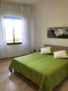 una camera con letto verde e finestra di Baia Taormina Apartment a Giardini Naxos