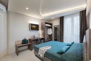 1 dormitorio con cama azul y escritorio en Hermes Hotel en San Vito lo Capo