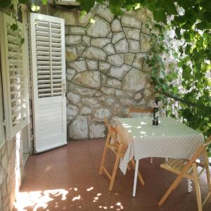 a table and chairs in front of a stone wall at Apartman Stipe in Jelsa