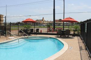a swimming pool with tables and chairs and umbrellas at Quality Inn & Suites Port Arthur - Nederland in Port Arthur