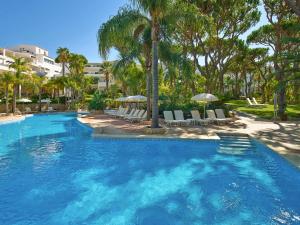 a large swimming pool with chairs and umbrellas at Vale Do Garrao Villas in Vale do Lobo