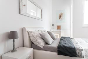 - une chambre blanche avec un lit et une table de nuit dans l'établissement Apartamenty Trzy Wieze, à Varsovie