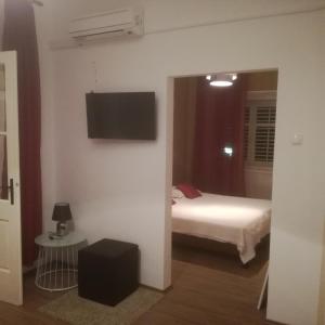 a bedroom with a bed and a tv on the wall at Apartman Stipe in Jelsa