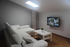 een woonkamer met een witte bank en een tv bij Be Happy in Algodonales