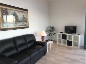 un soggiorno con divano nero e TV di Baia Taormina Apartment a Giardini Naxos
