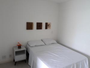 um quarto branco com uma cama e uma mesa de cabeceira em Beira Mar Praia Jatiúca em Maceió