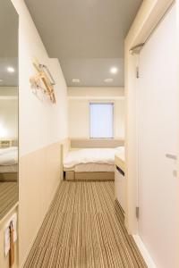 a small bedroom with a bed and a window at Belken Hotel Kanda in Tokyo