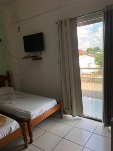 a room with two beds and a window with a television at Epílogo Palace Hotel in Rio Branco