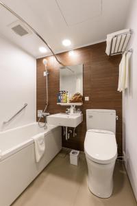 a bathroom with a toilet and a sink and a tub at Belken Hotel Kanda in Tokyo