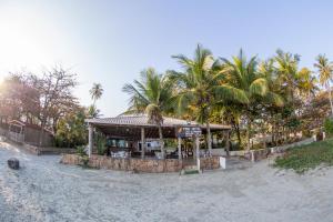 un restaurante en la playa con palmeras en el fondo en Pris Hotel, en Barequeçaba