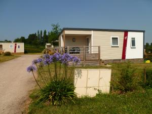 una casa con una puerta y flores púrpuras delante de ella en Camping le Frêche à l'Âne, en Pléboulle