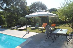 un tavolo e un ombrellone accanto alla piscina di La Petite Ferme du Marais a Saint-Germain-du-Bois