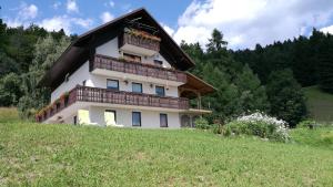 a building with a balcony on top of a field at Apartments Špik in Cerkno