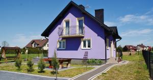 a purple house with a balcony on a street at Jagodowy Domek in Święta Katarzyna