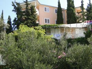 a large pink house with trees and bushes at Apartmani Tepli Bok in Primošten