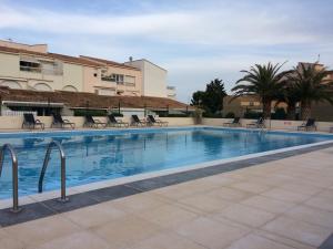 a swimming pool with chairs and a building at Résidence Port Soleil B453 in Cap d'Agde