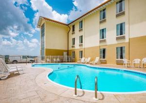 a pool in front of a hotel with chairs and a building at Savannah House Hotel in Branson