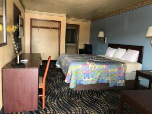 a hotel room with a bed and a desk and a bed sidx sidx at Deluxe Inn Kilgore in Kilgore