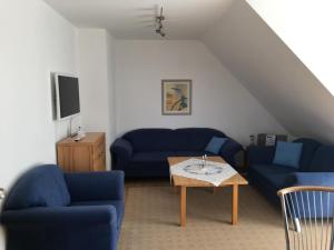 uma sala de estar com sofás azuis e uma mesa em Ferienwohnung Tietgens em Hohenfelde