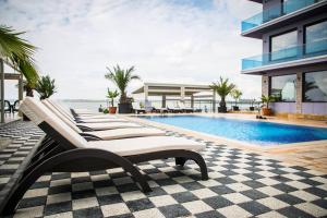 a row of white lounge chairs next to a swimming pool at Almar Lake View Boutique H in Mamaia