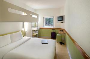 una camera da letto con un grande letto bianco e una televisione di ibis Budget - Campbelltown a Campbelltown