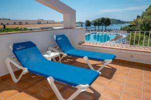 Duas cadeiras e uma mesa numa varanda com piscina em Hotel Calina em Cadaqués