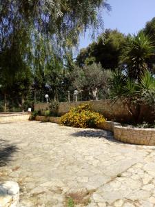une cour en pierre avec des fleurs et des arbres dans un parc dans l'établissement Villetta In Campagna, à Parabita