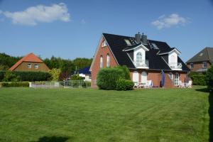 uma casa grande num quintal com um relvado verde em Ferienwohnung Tietgens em Hohenfelde