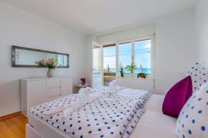 Dormitorio blanco con cama con almohadas azules y moradas en Jasmina apartment en Rijeka