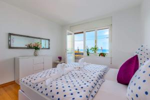 a white bedroom with a bed with blue and purple pillows at Jasmina apartment in Rijeka