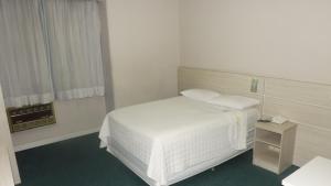 a bedroom with a white bed and a window at Rede Andrade San Martin in Curitiba