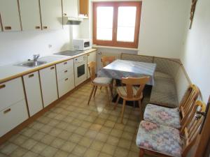 cocina con mesa, sillas y fregadero en Aparthotel Garni Haus Hubertus, en Malles Venosta