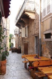 Un callejón con una mesa y bancos de madera. en Nona Zena, en Korčula