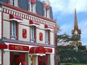 un bâtiment d'hôtel avec une tour d'horloge en arrière-plan dans l'établissement Hotel Du Parc, à Cabourg