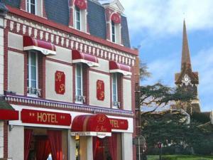 a hotel building with a clock tower in the background at Hotel Du Parc in Cabourg