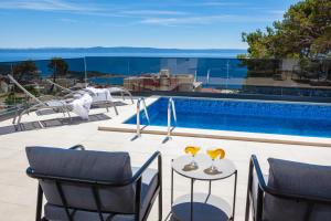 a patio with two glasses on a table next to a swimming pool at Villa MirA with fantastic sea view in Makarska