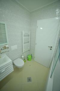 a white bathroom with a toilet and a shower at Hotel Vrata Bosne in Velika Kladuša