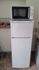 a microwave sitting on top of a white refrigerator at Chambre d'hôte à Saint-Pierre in Saint-Pierre