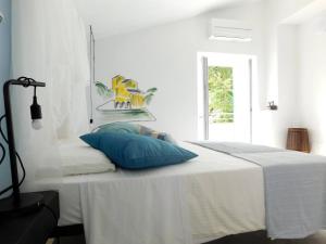 a white bedroom with a bed with a blue pillow at Il Ghiro in Levanto