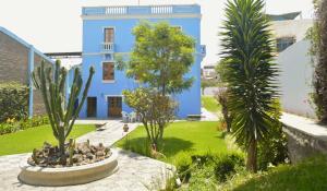 un bâtiment bleu avec des palmiers dans une cour dans l'établissement Las Mercedes, à Arequipa