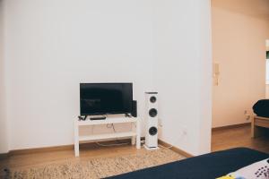 uma sala de estar com televisão numa mesa branca em A Casa do Jardim à Estrela I em Lisboa