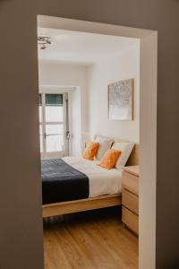 um quarto com uma cama com almofadas laranja em A Casa do Jardim à Estrela I em Lisboa